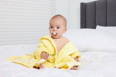 Bornozlu şirin bebek evde yatakta oyuncakla oynuyor.