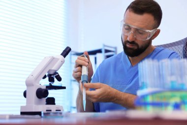 Genetik araştırması. Bilim adamı laboratuardaki masada mikro pipetle örnek alıyor.