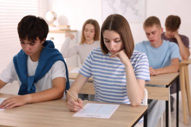 Ahşap masada sınava giren öğrenciler