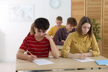 Ahşap masada sınava giren öğrenciler