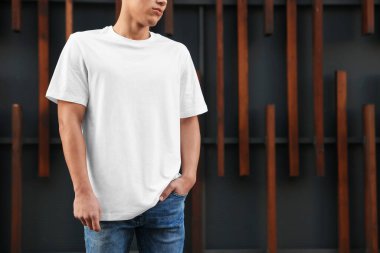 Duvarın yanında beyaz tişört giyen genç adam, yakın plan. Tasarım için model