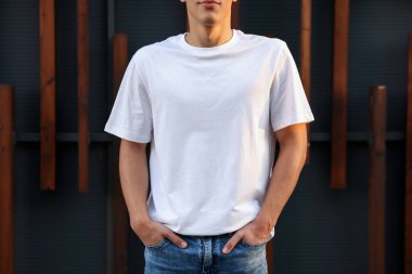 Duvarın yanında beyaz tişört giyen genç adam, yakın plan. Tasarım için model