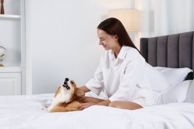 Evcil hayvan dostu otel. Güzel Galli Corgi köpeğiyle yatağında mutlu bir kadın.