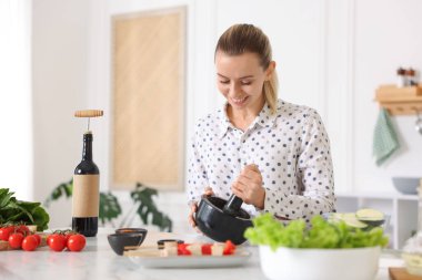 Mutfaktaki masada yemek yapan gülümseyen kadın.