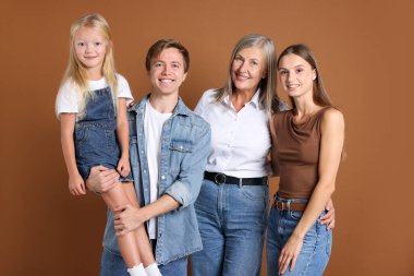 Kahverengi arka planda oğlu ve ailesi olan yaşlı bir kadının portresi.