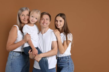 Kahverengi arka planda oğlu ve ailesi olan yaşlı bir kadının portresi.