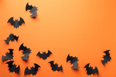 Cadılar Bayramı dekoru. Siyah kağıt yarasalar turuncu arka planda, düz yerde. Metin için boşluk
