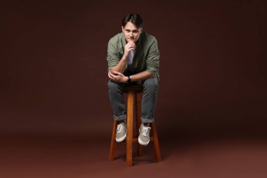 Kahverengi arka planda, kotlu şık bir adam.