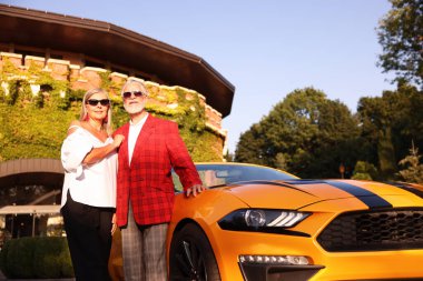 Modern Cabriolet yakınlarında güneş gözlüklü şık bir çift, düşük açılı.