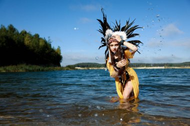 Kızılderili başlıklı güzel bir şaman kadın. Yüzü nehirde su sıçratıyor. Metin için boşluk