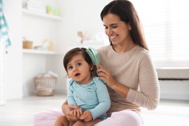 Anne banyoda bebeğinin saçını tarıyor.