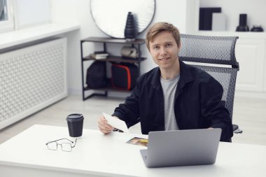 Stüdyoda beyaz masada çalışan profesyonel fotoğrafçı. Mesaj için yer var.