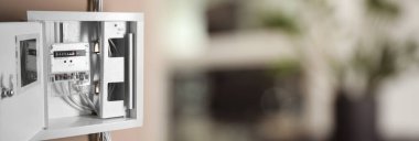 Electricity meter in fuse box on wall indoors. Banner design