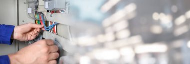 Elektrikçi evin içine elektrik sayacı yerleştiriyor, yakın plan. Pankart tasarımı