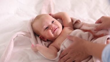 Anne bebeğini havluyla örtüyor. Yatakta banyo yaptıktan sonra, yakın plan.