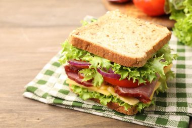 Delicious sandwich with ham, cheese and vegetables on wooden table, closeup. Space for text