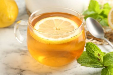 Beyaz mermer masada limonlu, naneli ve kaşıklı Aromatik çay, yakın plan.