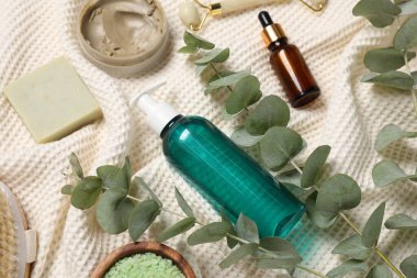 Composition with spa products and eucalyptus branches on bathrobe, above view