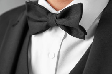 Gri arkaplanda şık papyonlu takım elbiseli adam, yakın plan.