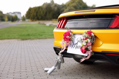 Düğün arabası. Cabriolet, Yeni Evli kartıyla dekore edilmiş, güzel çiçekler ve teneke kutular, yakın plan. Metin için boşluk