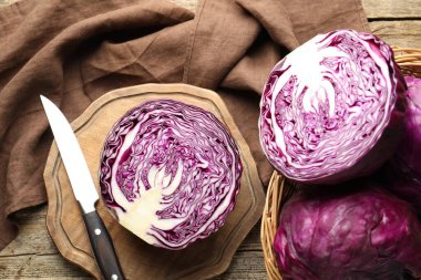Fresh ripe red cabbages and knife on wooden table, flat lay
