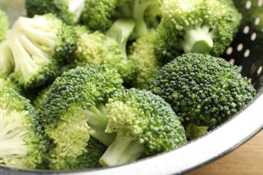 Fresh raw broccoli in colander on table, closeup