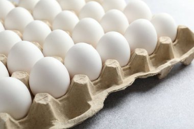 Yumurta kutusunda çiğ tavuk yumurtası. Gri masada, yakın plan.