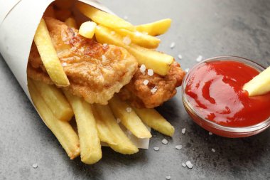 British Traditional Fish and chips with sauce on grey table, closeup