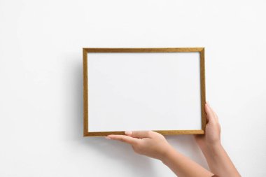 Beyaz duvara boş bir diploma çerçevesi asan kadın, yakın plan. Tasarım için model