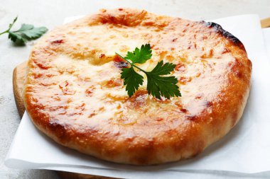 Delicious Megrelian khachapuri with parsley on grey table, closeup