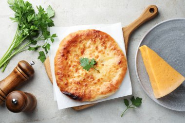 Delicious Megrelian khachapuri with ingredients on grey table, flat lay
