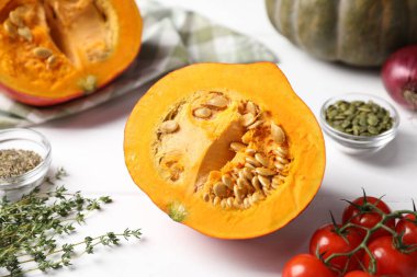 Fresh pumpkins, spices and tomatoes on white wooden table, closeup