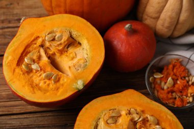 Fresh pumpkins and seeds on wooden table, closeup