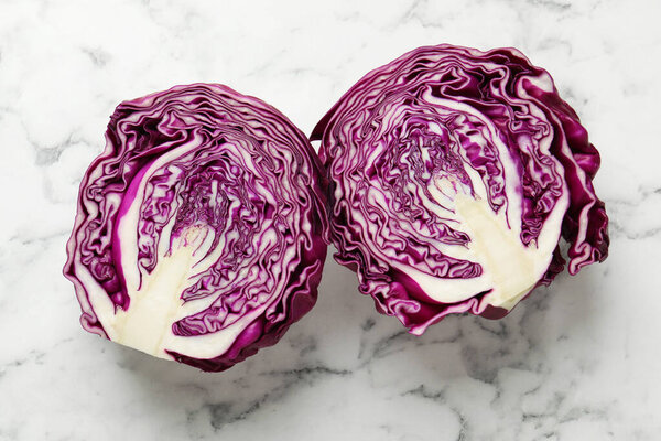 Cut red cabbage on white marble table, top view