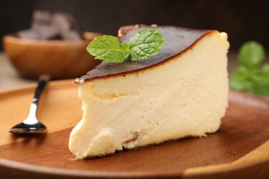 Piece of delicious Basque cheesecake with mint on table, closeup