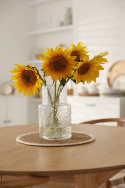 Evdeki ahşap masada vazoda güzel ayçiçekleri
