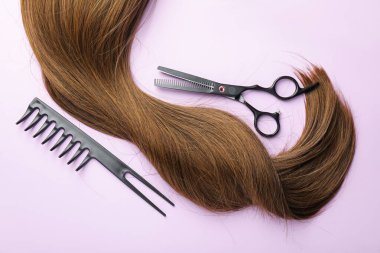 Güzel kahverengi saçlar, makas ve açık mor arkaplan tarağı, üst görünüm