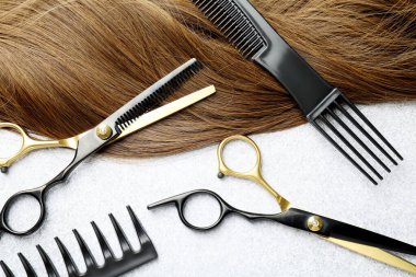 Beautiful hair strand and hairdresser's tools on light background, flat lay
