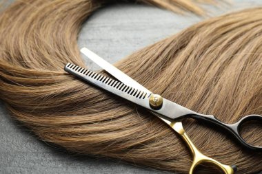 Gri arka planda güzel saç teli ve makas, yakın plan.