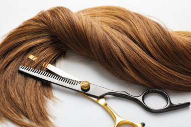 Beyaz arka planda güzel saç teli ve makas, yakın plan.