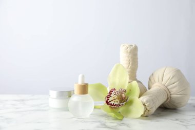 Beautiful spa composition with herbal bags and essential oil on white marble table against light background. Space for text