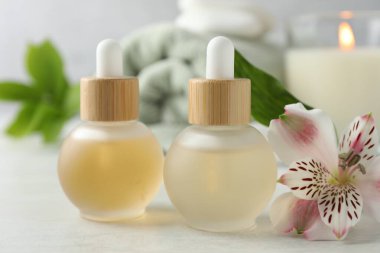 Essential oils and floral decor on white table, closeup