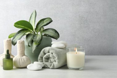 Beautiful spa composition with herbal bags and burning candle on white table, space for text