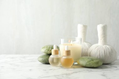Beautiful spa composition with herbal bags and burning candle on white marble table, closeup. Space for text