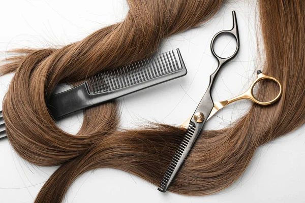 Güzel kahverengi saç, makas ve tarakla beyaz arka plan, üst manzara