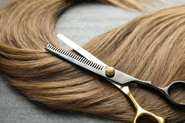 Gri arka planda güzel saç teli ve makas, yakın plan.
