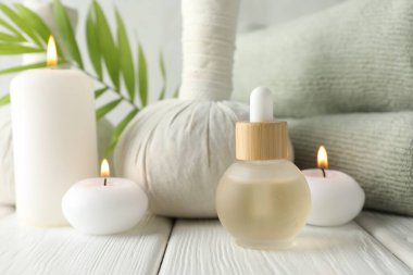 Beautiful spa composition with herbal bag and burning candles on white wooden table, closeup