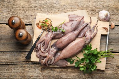 Raw squids, stuffing and parsley on wooden table, flat lay