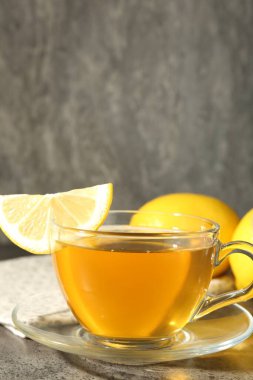 Aromatic tea in cup with lemons on grey table, closeup