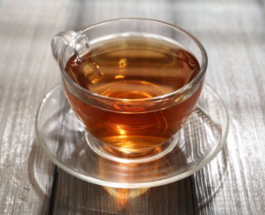 Aromatic black tea in glass cup on wooden table, closeup